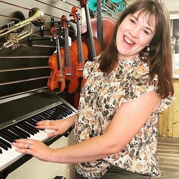 Woman smiling while playing keyboard in a music store.