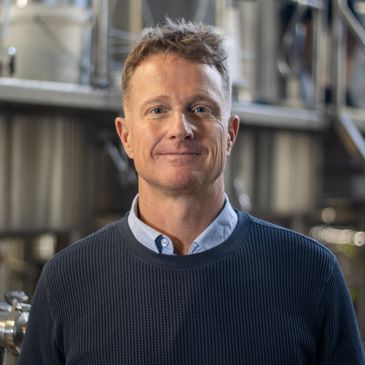 Man smiling in a brewery setting.