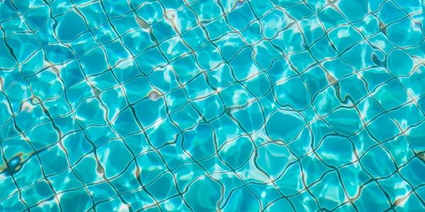 Clear blue water with tile grid pattern in a swimming pool.