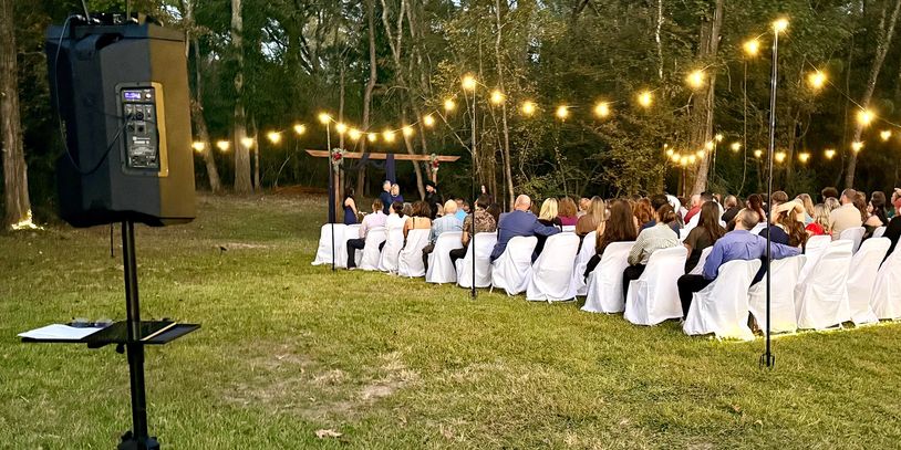 Outdoor wedding ceremony with string lights and DJ sound setup in Louisiana