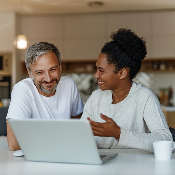 A man in his forties is learning more about his wife's menopause symptoms at their kitchen computer.