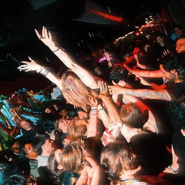 Crowd surfing at a lively concert with vibrant lighting.