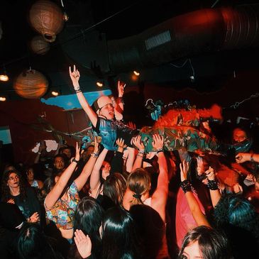 Person crowd surfing at a lively concert with enthusiastic audience.