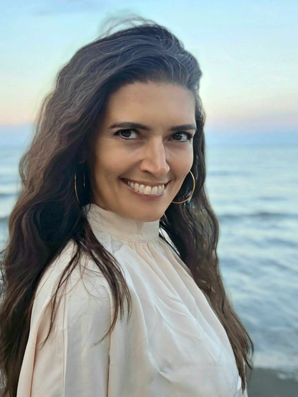 Smiling woman with long hair by the beach.