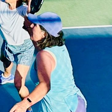Two women playing pickleball on a court.
