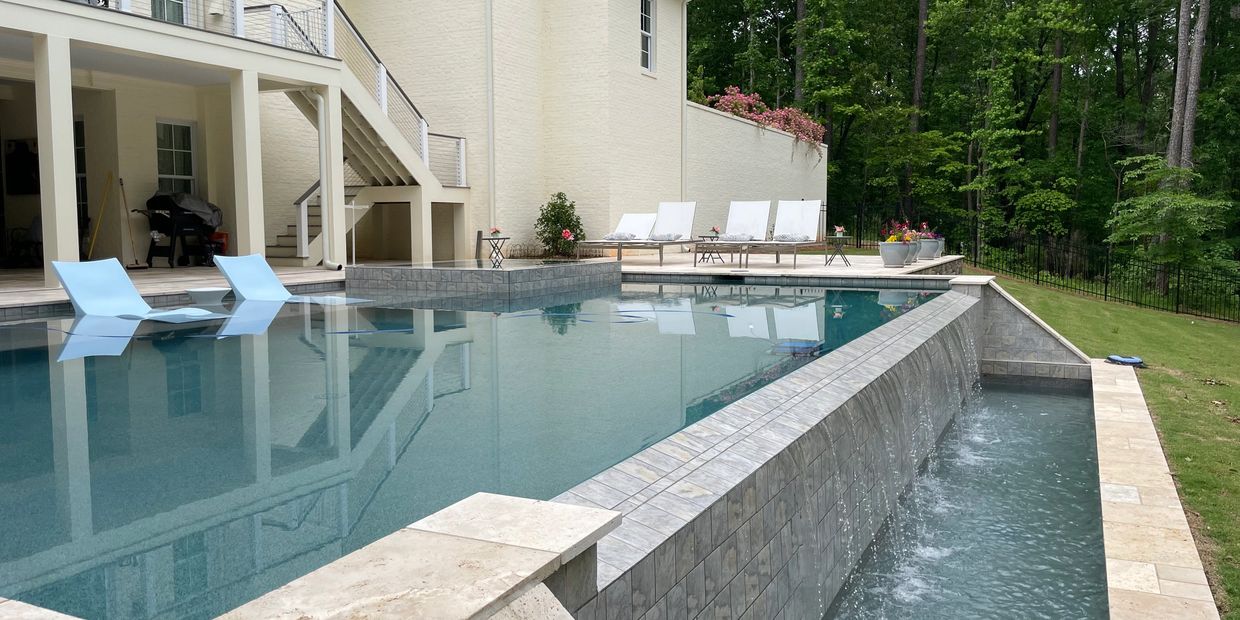 Elegant backyard pool with cascading water feature and lounge chairs.