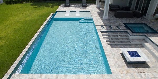 Modern backyard pool with lounge chairs and a fire pit.