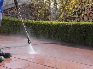 Man performing a power wash on patio. 