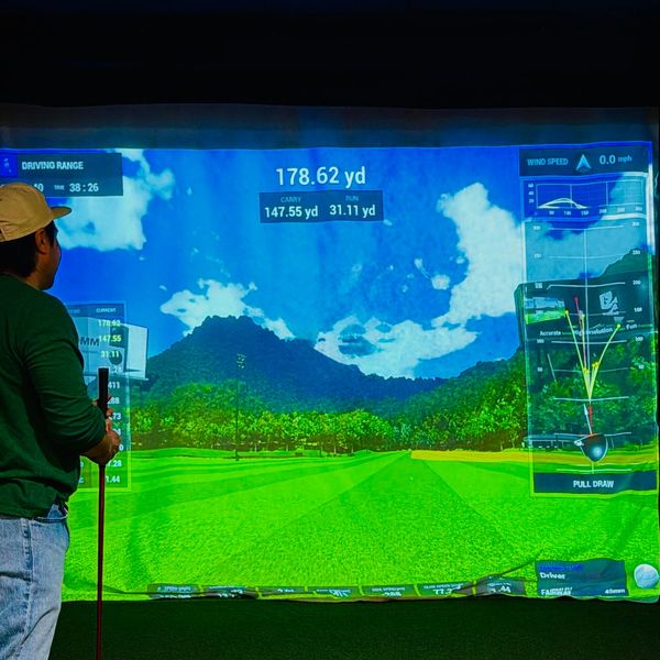 Person playing golf on an indoor simulator with detailed gameplay stats.