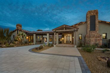 Modern desert-style home at dusk with stone driveway.