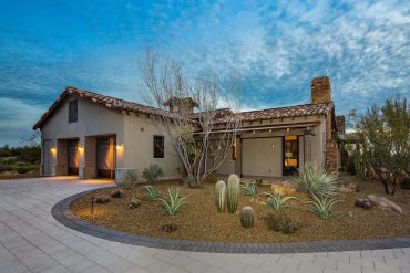 Modern desert home with cacti landscaping at dusk.