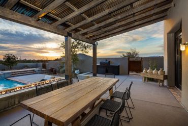 Outdoor patio with pool and dining area at sunset.