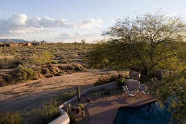 Desert landscape with a pool and patio at sunset.