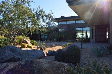 Modern house with desert landscaping and large rocks.