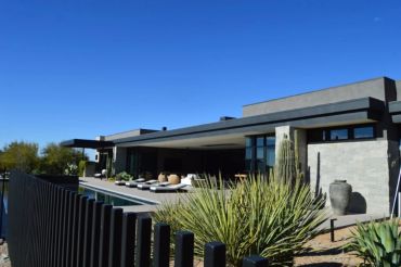 Modern house with outdoor seating and clear sky.