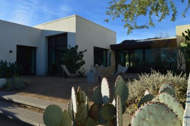 Modern house with desert landscaping and cacti.