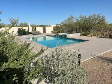 Outdoor swimming pool with lounge chairs under clear sky.