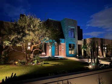 Modern house lit up at night with blue and white lighting.