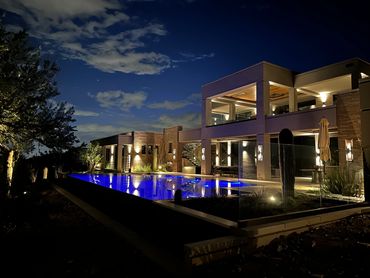 Modern house with lit pool at night.