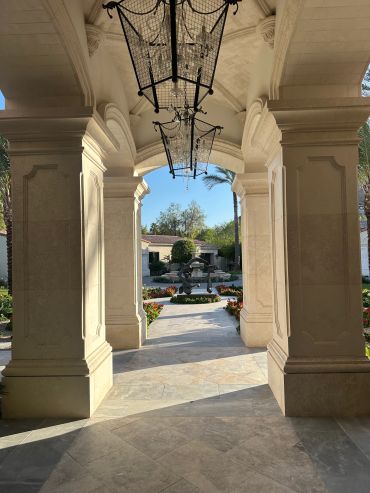 View of a garden fountain through a stone archway.