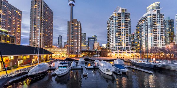 Boats docked at a marina with city skyline at dusk.