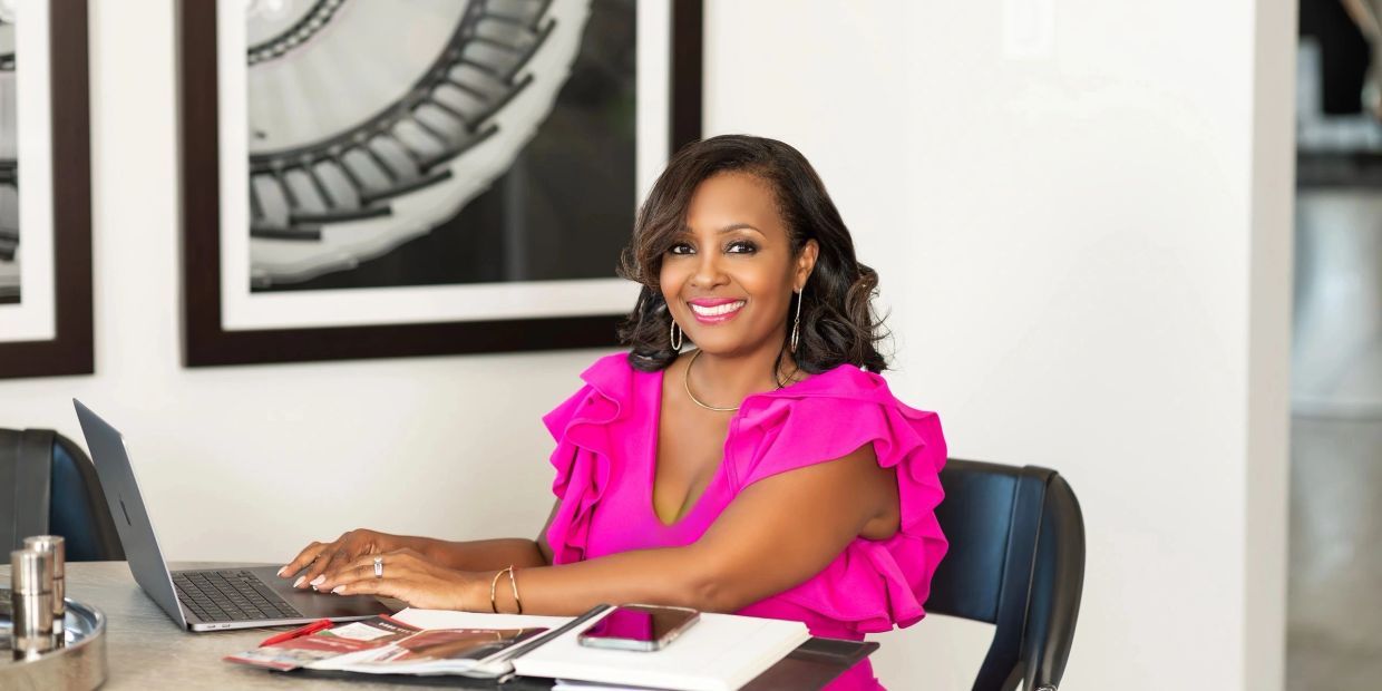 Confident woman in pink working on laptop in a bright office.