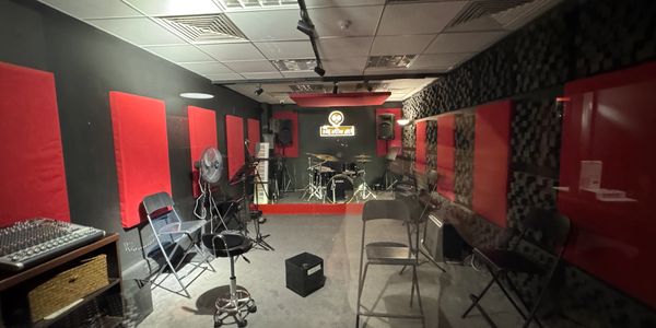 Music rehearsal room with instruments and chairs.