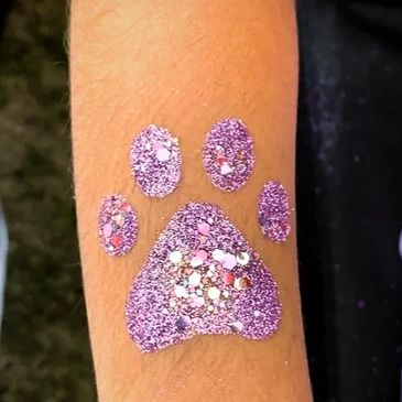 Arm with lavender paw print glitter tattoo.