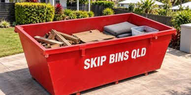 Household clean-out materials below the rim of a red Skip Bins QLD bin. Illustrative image.