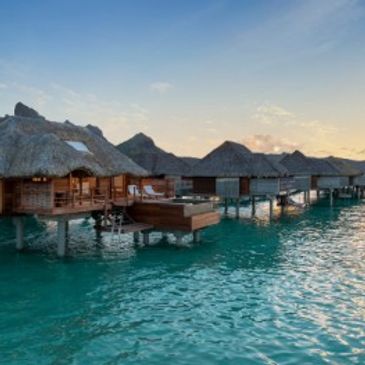 Overwater bungalows at sunset on a tropical island.