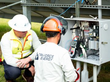 Technicians inspecting solar electrical equipment during construction.