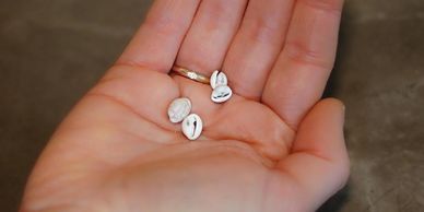 Hand holding three small white pills or tablets.