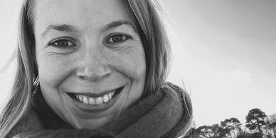 Black and white close-up of a smiling woman outdoors.