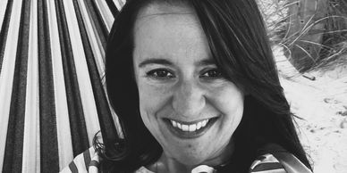 Black and white close-up of a smiling woman in a hammock.