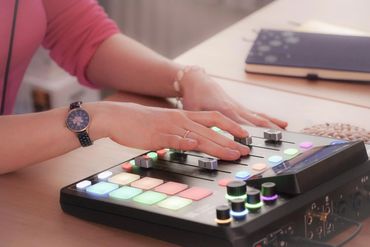 Person adjusting audio mixer controls in a studio setting.
