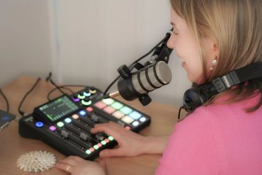 A woman speaking into a microphone with audio mixing equipment.