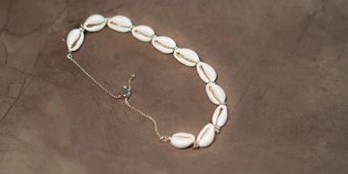 A delicate necklace made of white seashells on a brown surface.
