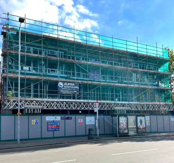 Building under construction with scaffolding and safety signs.