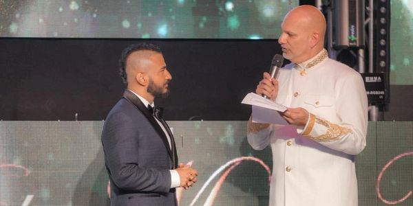 Two men in formal attire engaged in conversation on stage.