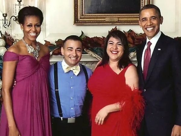 Four people smiling together in formal attire, including Michelle and Barack Obama.