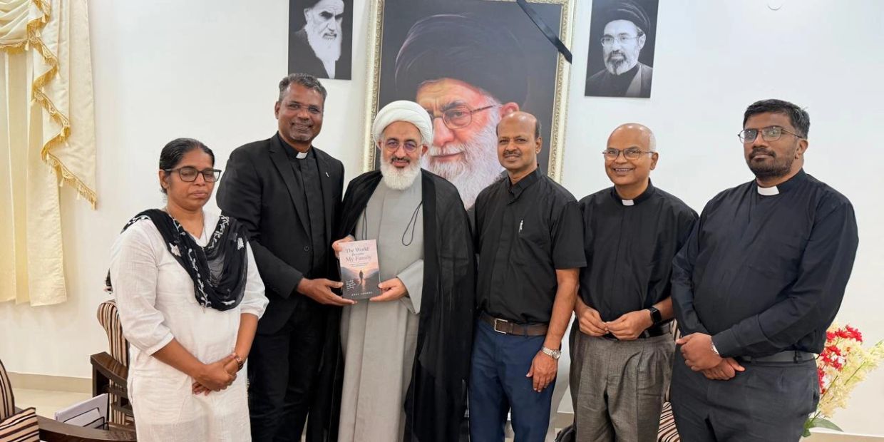 Group of six people posing indoors, one holding a book.