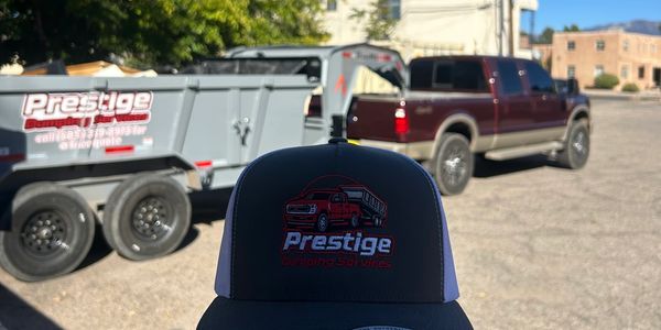 Hat with Prestige logo in front of a truck and trailer.