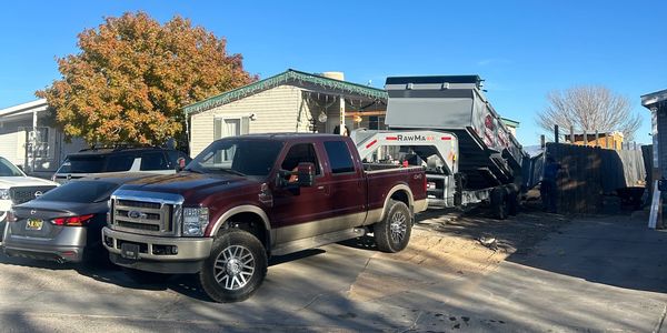 A maroon pickup truck parked in front of a house on a sunny day.