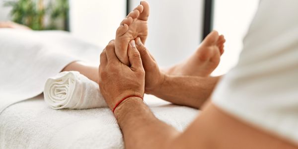 Latin man and woman covered with a towel laying on a mobile massage bed having massaging feet at bea