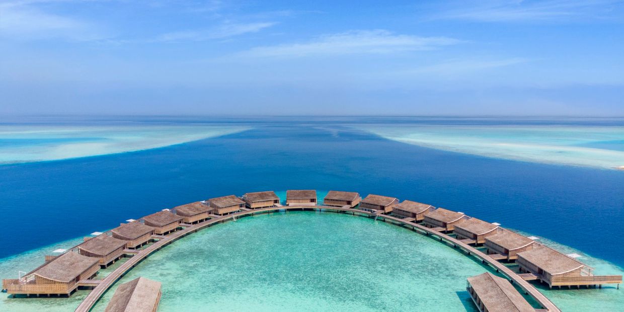 Kudadoo Maldives Private Island luxury overwater villas set above crystal-clear turquoise waters.