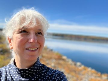 Jennie smiling beneath a bright blue sky along the shore of the Quabbin Reservoir.