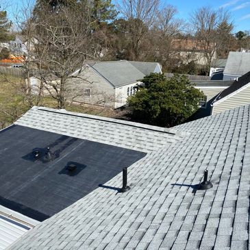 Residential rooftops with shingles and vents under clear sky.