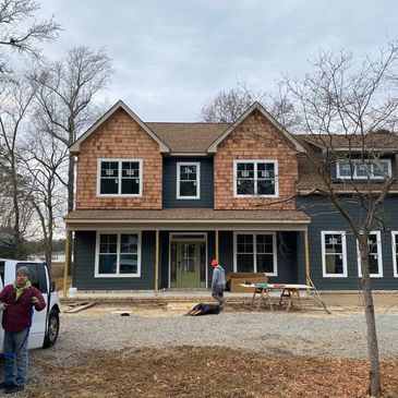 Two-story house under construction with workers outside.