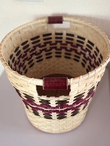 Handwoven basket with purple and black patterns.