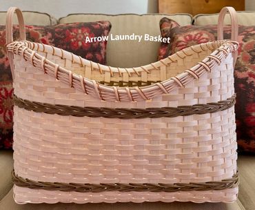 Pink woven laundry basket with handles and brown accents.